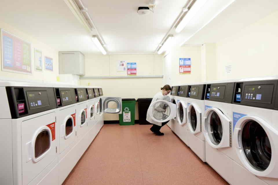 A student loading a washing machine in the launderette